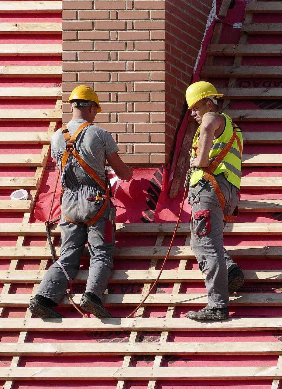 Two construction workers on a rooftop working with chimney bricks.