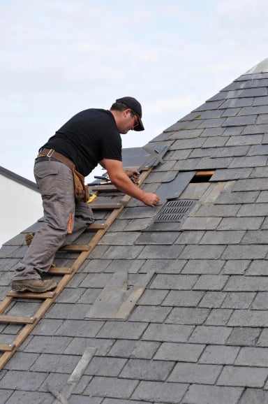 Roofer installing shingles on a sloped roof