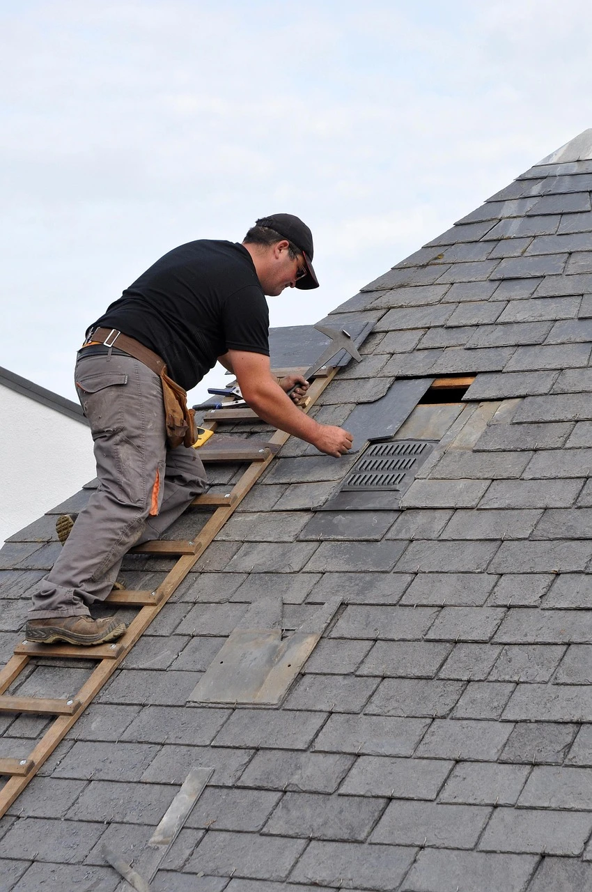 Roofer installing shingles on a sloped roof
