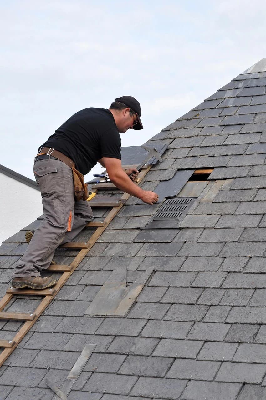 Roofer installing shingles on a sloped roof